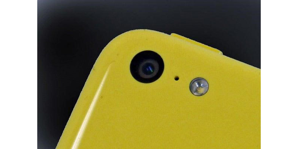 موبایل زرد رنگ در پس زمینه سیاه قرار دارد و دوربین 5c از نزدیک دیده می شود