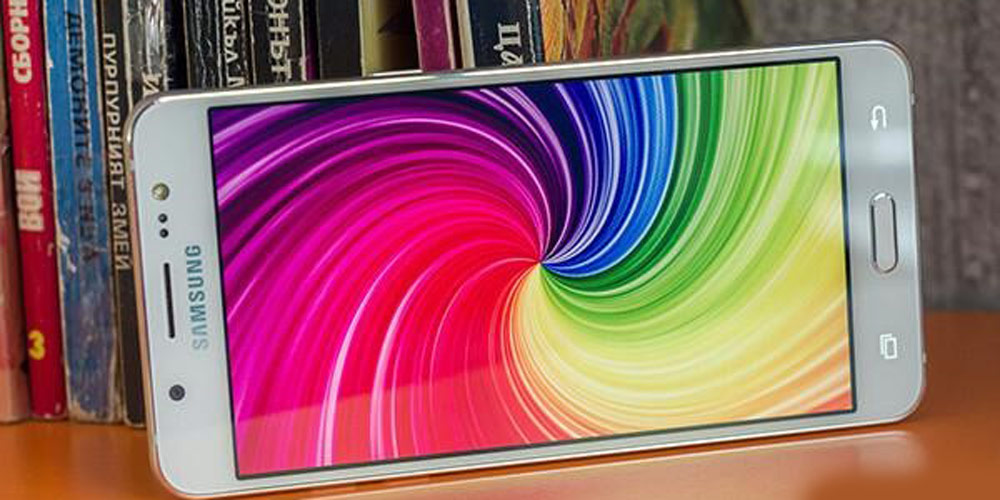 موبایل جلوی کتابخانه قرار دارد و ال سی دی جی 5 (2016) تصویری رنگارنگ را نمایش می دهد