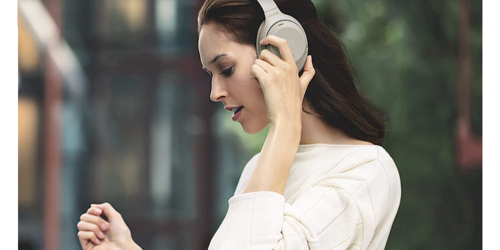 زن هدفون سونی WH-1000XM3 را روی گوش خود گذاشته و به موسیقی گوش می کند