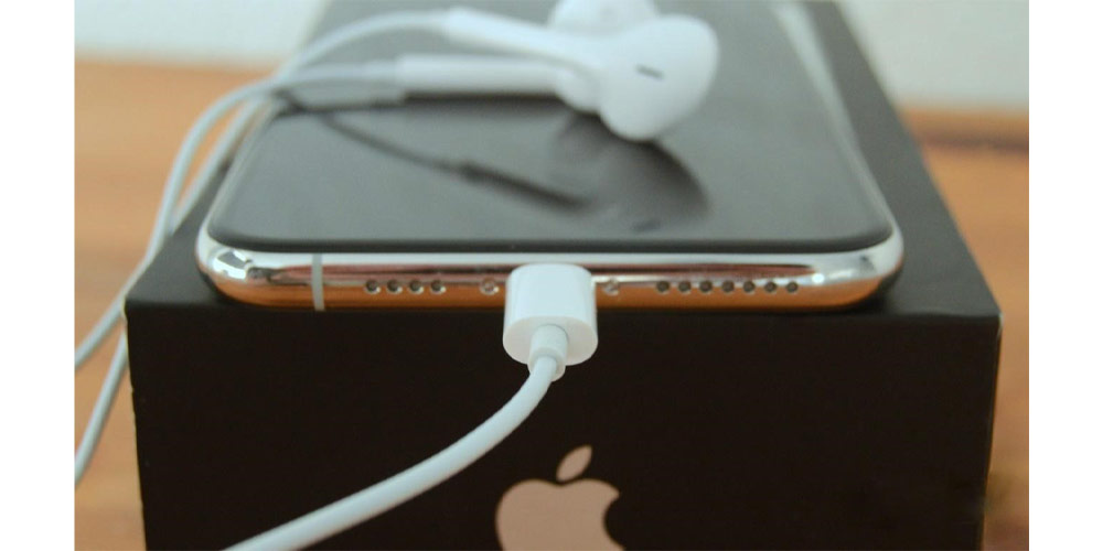 کابل شارژ آیفون 11 پرومکس به موبایل متصل شده و گوشی بر روی جعبه اپل قرار دارد