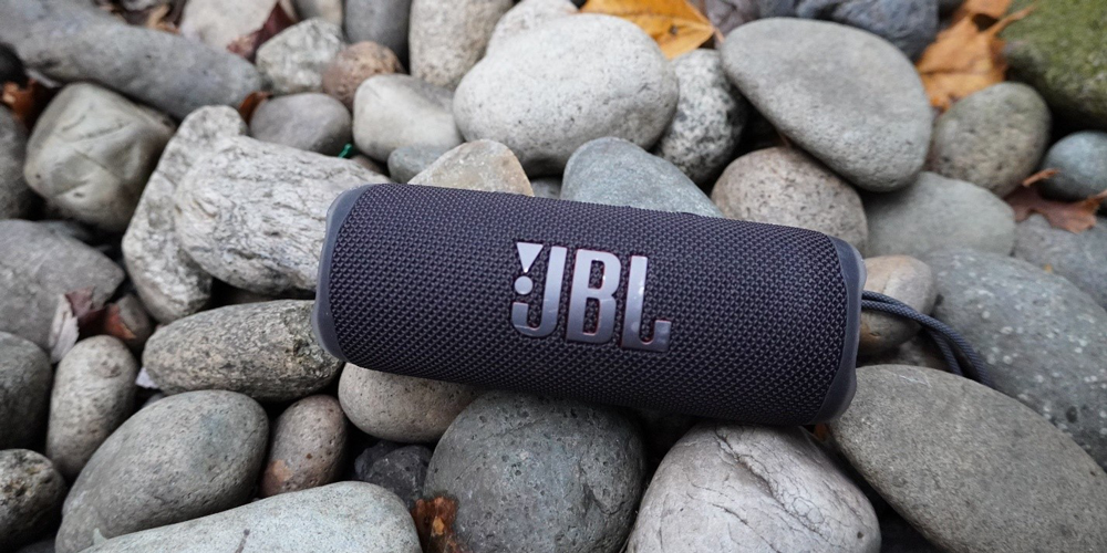 JBL Flip 6 مشکی روی تختی از سنگ های صاف